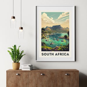 Könnte beinhalten: Ein gerahmter Kunstdruck mit einer malerischen Ansicht von Südafrika. Das Kunstwerk zeigt eine Küstenlandschaft mit Booten, Palmen und einer Bergkette unter blauem Himmel. Der Text "SOUTH AFRICA" ist unten aufgedruckt.