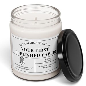 May include: A white soy wax candle in a glass jar with a black lid. The label reads "The Calming Scent of Your First Published Paper!"  It is a 9 oz candle made in the US and is organic and non-toxic.