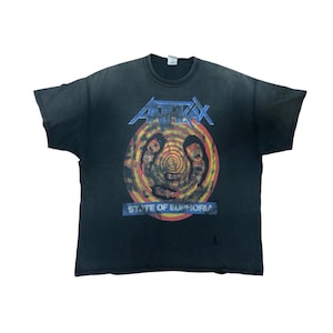 Puede incluir: Camiseta negra de la banda Anthrax con un gráfico circular con dos figuras y el texto "STATE OF EUPHORIA". El logotipo de la banda está en azul en la parte superior. La camiseta es vintage y muestra signos de desgaste.