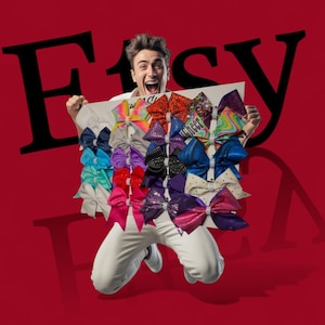 May include: A person holding a display of colorful hair bows. The bows are in various colors and patterns, including glitter, polka dots, and rainbow designs. The word "Cheer" is visible on one of the bows.