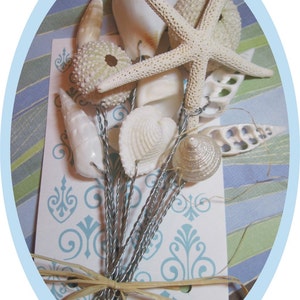 May include: A bouquet of seashells, starfish, and sea urchins tied together with twine. The shells are white and beige and are arranged on a white background with a blue and green patterned design.