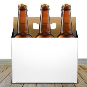 May include: A six-pack of brown glass beer bottles with gold bottle caps, inside a cardboard carrier with a white exterior. The bottles are filled with a golden liquid. The carrier has a handle cut out at the top.