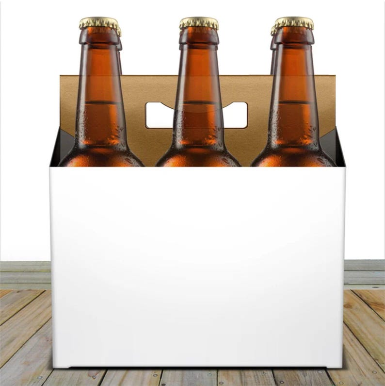 May include: A six-pack of brown glass beer bottles with gold bottle caps, inside a cardboard carrier with a white exterior. The bottles are filled with a golden liquid. The carrier has a handle cut out at the top.