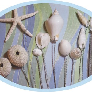 May include: A collection of white seashells and starfish on wire stems, arranged on a blue and green striped background.