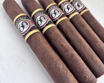 May include: Five brown cigars with bands that read "look who's 60". The bands are black, red, and gold with a portrait of a woman. The cigars are arranged diagonally on a white surface.