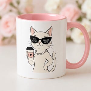 Puede incluir: Taza de cerámica blanca con interior y asa rosas. La taza presenta un gato de dibujos animados con gafas de sol con el texto "plot twist i don't care" y sosteniendo una taza de café. Un collar de perlas está alrededor del cuello del gato.