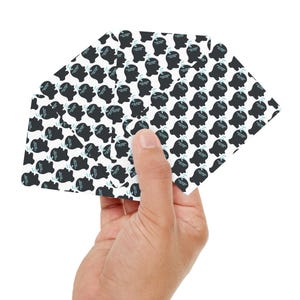 May include: A stack of white cards with a black and blue pattern of a person's head with a thought bubble. The cards are being held in a hand.