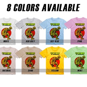 May include: Eight color variations of a t-shirt featuring a graphic of the Thing from the Fantastic Four. The text "THING" is printed in yellow above the graphic. The colors are white, ash grey, sky blue, pink, natural, sand, yellow, and mint.