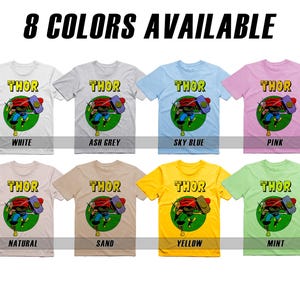 May include: Eight t-shirts featuring a comic book character with the word "THOR" printed on the front. The t-shirts are available in eight colors: white, ash grey, sky blue, pink, natural, sand, yellow, and mint.