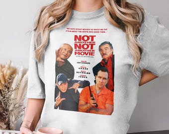 May include: White t-shirt with a movie poster design for "Not Another Not Another Movie." The design features images of actors and the film's title. The shirt has a crew neck and short sleeves, a popular style in the UK.