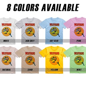 May include: Eight t-shirts featuring a cartoon image of Wolverine in a yellow circle with the word "WOLVERINE" in red above the image. The t-shirts are available in the following colors: white, ash grey, sky blue, pink, natural, sand, yellow, and mint.