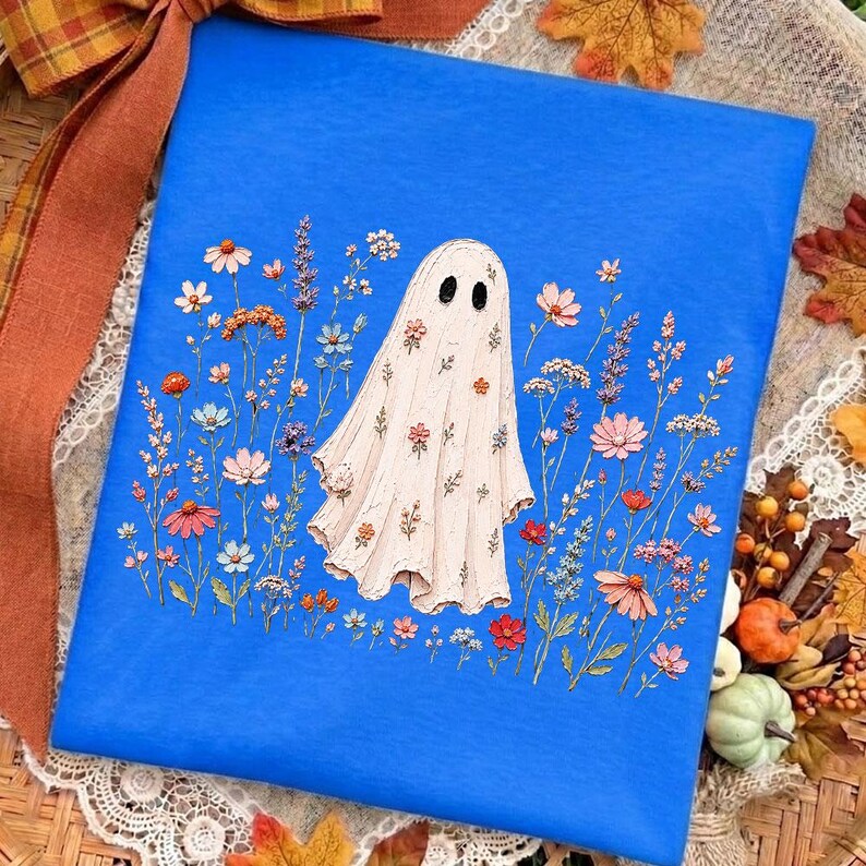 May include: A bright blue rectangular surface featuring a central illustration of a white ghost covered in small colorful flowers. The ghost is surrounded by a variety of delicate wildflowers in shades of pink, orange, blue, and purple.