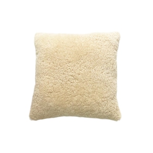 May include: A cream-coloured, fluffy pillow made of faux fur. The pillow is square-shaped and has a soft, plush texture.