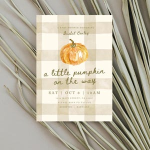 Może przedstawiać: Zaproszenie na baby shower z akwarelową ilustracją dyni. Zaproszenie ma beżowo-białe kratkowane tło i tekst "a little pumpkin on the way". Szczegóły obejmują datę, godzinę i miejsce.