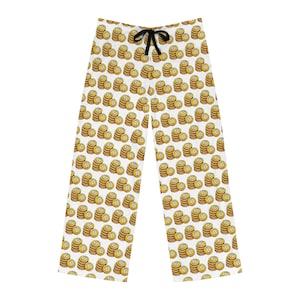 May include: White pajama pants with a repeating pattern of gold coins with a "B" symbol. The pants have a black drawstring at the waist. The coins are stacked in piles on the fabric.