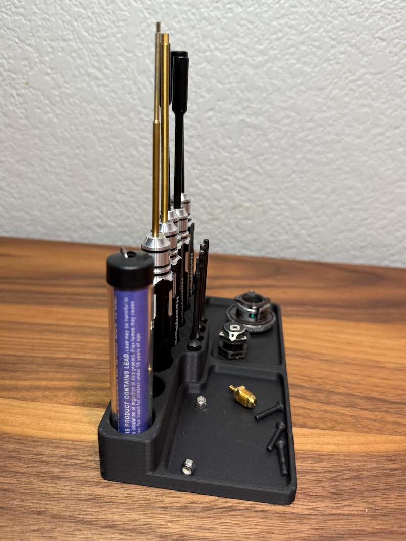 May include: A black plastic tool organizer with a variety of tools, including screwdrivers, a small tube of lubricant, and a few small parts. The organizer has a compartment for each tool and a small tray for the parts.