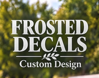 May include: A frosted decal applied to a transparent surface featuring the white text FROSTED DECALS in a bold serif font, a small leaf graphic centered below, and the text Custom Design in a smaller serif font underneath.