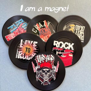 May include: A set of black magnets with vibrant graphics. Each magnet displays a unique design, such as a skull, a hand symbol, and the words "ROCK", "HIP HOP", and "CRAZY MUSIC". The text "I am a magnet" is written in white.