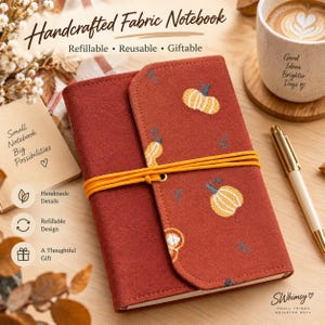 Puede incluir: Un cuaderno de tela con una cubierta de color óxido que presenta un patrón bordado de calabazas amarillas y blancas. El cuaderno está asegurado con una banda elástica de color amarillo brillante y tiene el texto Handcrafted Fabric Notebook.