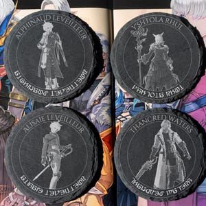 May include: Four circular black slate coasters featuring laser-engraved character illustrations and names. The coasters depict Alphinaud Leveilleur, Y'shtola Rhul, Alisaie Leveilleur, and Thancred Waters, each surrounded by circular text in a fantasy script.