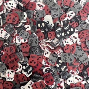 May include: A collection of skull-shaped decorative sprinkles in various colors. The sprinkles are in red, white, black, and gray, with detailed facial features and bone designs. These Halloween-themed sprinkles are ideal for decorating baked goods.