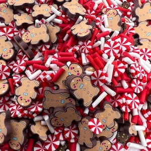 May include: A close-up of a variety of Christmas sprinkles, including gingerbread men, candy canes, and red and white sprinkles.