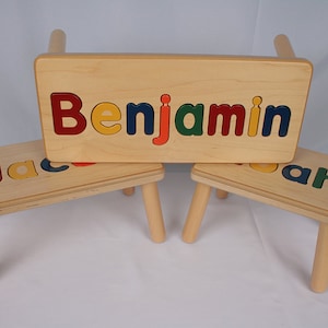 May include: Three wooden children's stools with personalized names spelled out in colorful letters. The stools are made of natural wood and have a simple design. The names on the stools are "Benjamin", "Jacob", and "Noah".