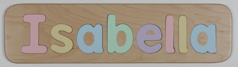 May include: A wooden puzzle with the name "Isabella" spelled out in colorful letters. The letters are pink, yellow, blue, green, purple, and yellow.