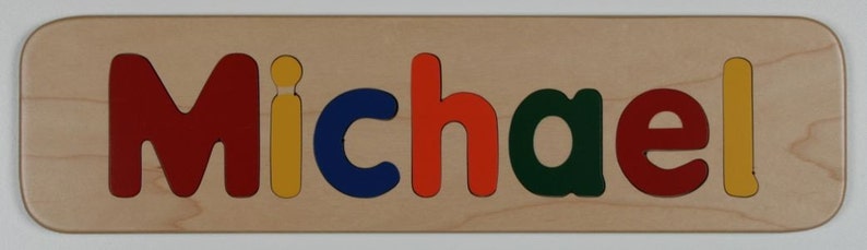 May include: Wooden puzzle with the name "Michael" spelled out in colorful letters. The letters are red, yellow, blue, orange, green, and red.