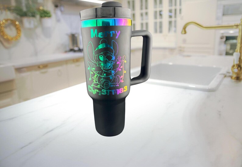 May include: A black stainless steel travel mug with a rainbow iridescent design featuring a cartoon character and the text "Merry Christmas".