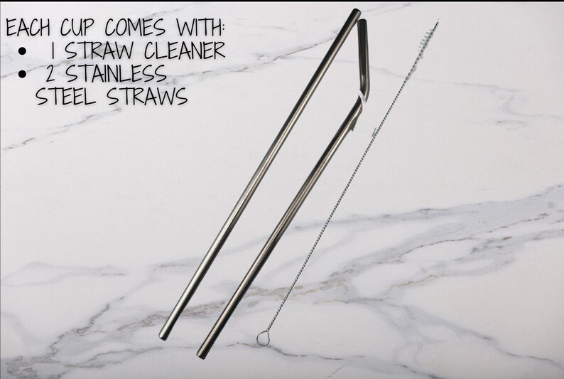 May include: Two silver metal straws and a silver straw cleaning brush on a white marble surface.  The text "EACH CUP COMES WITH: 1 STRAW CLEANER 2 STAINLESS STEEL STRAWS" is visible in the top left corner of the image.