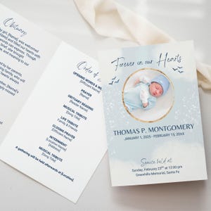 May include: A memorial service program with a blue watercolour background. The cover displays a baby's photo, the text "Forever in our Hearts," and the name and dates of the deceased. The inside includes an obituary and order of service details.