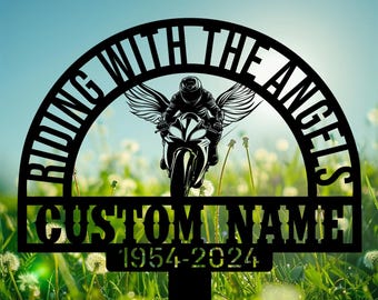 May include: Black metal memorial garden stake with the text "Riding with the Angels" in a half-circle arch above the text "CUSTOM NAME 1954-2024". The stake features a silhouette of a motorcycle rider with angel wings.