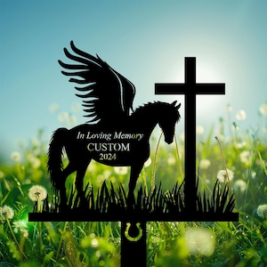 May include: Black metal silhouette of a horse with wings, standing in front of a cross. The horse has the text "In Loving Memory CUSTOM 2024" on its side. The silhouette is set against a background of green grass and white dandelions.