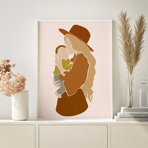 May include: Abstract art print featuring a mother holding a child. The artwork uses a palette of warm earth tones, including brown, tan, and olive green, with a minimalist style. The mother wears a hat, and the child is in her arms.