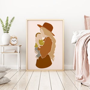 May include: A framed art print featuring an abstract illustration of a person holding a child. The artwork uses a palette of warm earth tones, including shades of brown, beige, and olive green. The figures are stylized with simple lines and shapes, creating a modern and minimalist aesthetic.