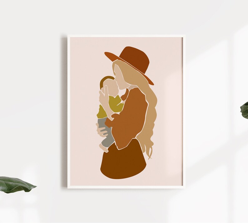 May include: Abstract art print featuring a mother holding a child. The artwork uses a minimalist style with warm earth tones, including shades of brown, tan, and olive green. The mother wears a wide-brimmed hat. The print is framed in a white border.