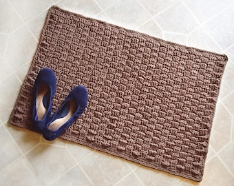 May include: A brown crocheted rug with a woven texture. Two blue suede shoes are placed on the rug.