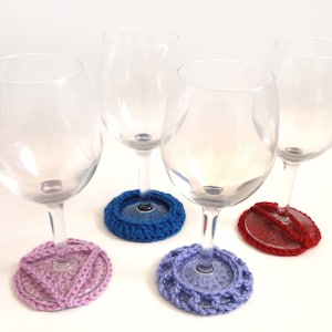 May include: Four wine glasses with crocheted coasters in purple, blue, red and light purple.