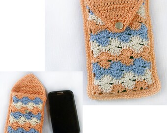 Puede incluir: Una funda de teléfono de ganchillo en color melocotón, blanco y azul. La funda tiene una solapa con cierre de botón.