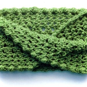 Op de afbeelding: Een groene gehaakte hoofdband met een textuurpatroon. De hoofdband is dubbelgevouwen en heeft een losse, vloeiende stijl.