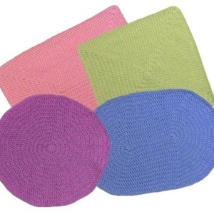Puede incluir: Cuatro alfombras de crochet en diferentes colores y formas. Una alfombra cuadrada rosa, una alfombra cuadrada verde, una alfombra redonda morada y una alfombra ovalada azul.