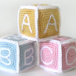 May include: Three crocheted alphabet blocks, one yellow with the letter A, one light blue with the letter B, and one pink with the letter C.