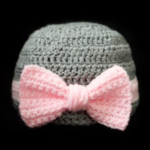 May include: A gray crocheted hat with a pink crocheted bow.