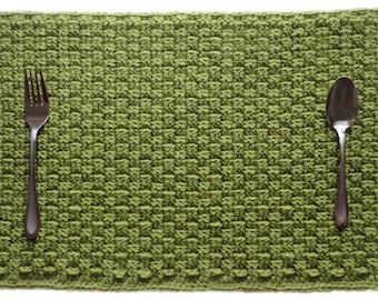 Peut inclure: Un set de table en crochet vert avec une fourchette et une cuillère dessus.