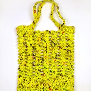 May include: A yellow crocheted tote bag with a mesh design. The bag is made from recycled plastic and has a bright yellow color with green and red accents.