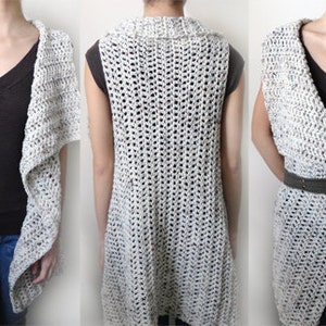 May include: A white crocheted vest with a draped collar and a loose fit. The vest is shown being worn with a black shirt and blue jeans.