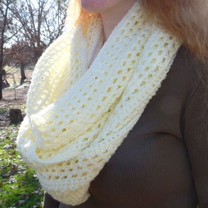 May include: A white crocheted infinity scarf with a delicate openwork pattern.