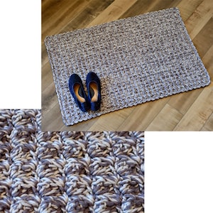 May include: A close-up of a crocheted rug with a brown and white color scheme. The rug is made with a textured stitch that creates a raised pattern. The rug is lying on a wooden floor.