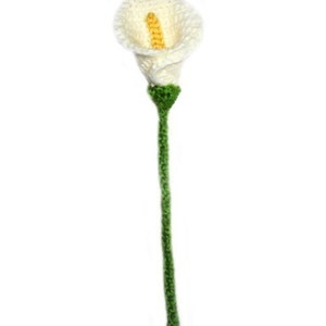 May include: A white crocheted calla lily with a yellow center and a green stem.